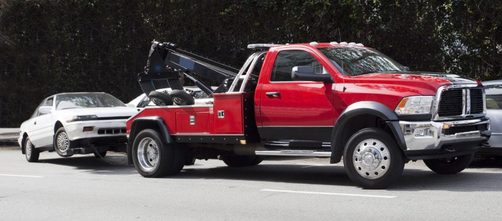 Red truck towing a small white car