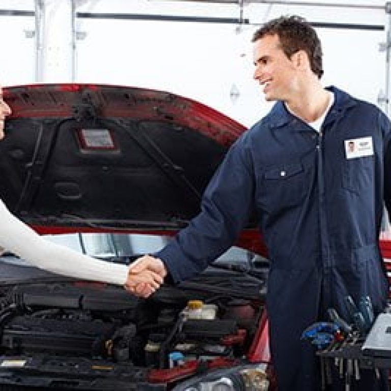 Handsome mechanic and client woman in auto repair shop.